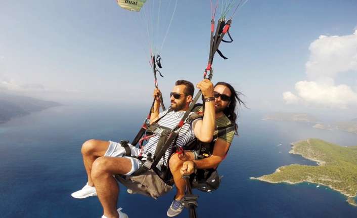 Muğla’nın Fethiye ilçesinde ilk kez yamaç paraşütü deneyimi yaşayan tatilci,