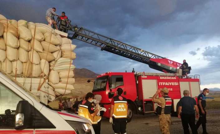 Erzincan'da yağmura yakalanan saman yüklü aracın üzerine branda çekmeye çalışan